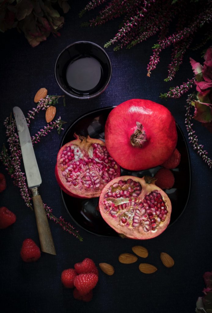 Pic by nathalie jolie for unsplash - Whole and cut Pomegranates, strawberries, and lavender, and a knife on a dark tablecloth